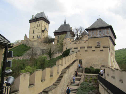 hrad Karlštejn a kaple sv.Kříže - Základní kámen nejvýznamnějšího a bezesporu nejznámějšího českého hradu byl položen římským císařem a českým králem Karlem IV. roku 1348 mimo jiné za účelem uložení korunovačních klenotů a svatých ostatků. Dnešní podoba je výsledkem zásadní přestavby v letech 1887-99, která ve snaze vrátit hradu gotický vzhled setřela do značné míry i prvky předchozích slohů. Jednou z nejvzácnějších částí Karlštejna je kaple sv. Kříže - místo uložení korunovačních klenotů a svatých ostatků. Pozlacená klenba spolu se 127 deskovými obrazy mistra Theodorika vytváří jeden z nejzachovalejších gotických interiérů na světě.
Pro návštěvu si můžete zvolit některý ze 3 prohlídkových okruhů, které vás provedou soukromými i reprezentačními komnatami Karla IV., Mariánskou nebo Velkou věží, Hradním lapidáriem a také zmiňovanou kaplí sv. Kříže.
